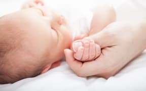 Newborn baby holding mother's thumb. (file pic)