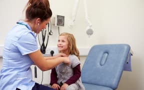 A nurse examines a young girl.