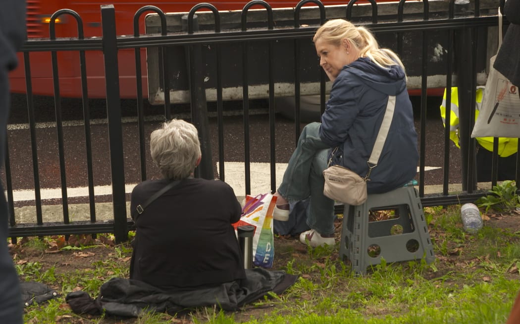 Sue Neenan and Deborah James wait on the fence line at Constitution Hill for hours to get a glimpse of the Queen’s hearse.