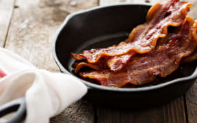 Sizzling hot bacon pieces in a cast iron skillet