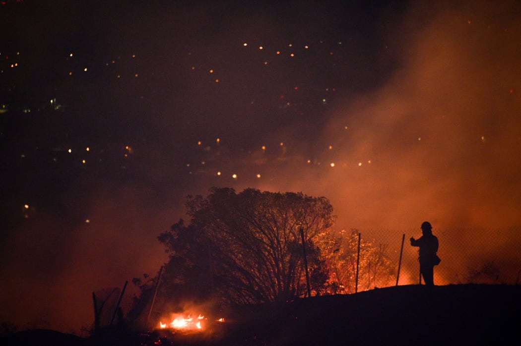 Firefighters position in a residential area and monitor flames climbing a ridge toward homes at the Blue Ridge Fire in Yorba Linda, California.