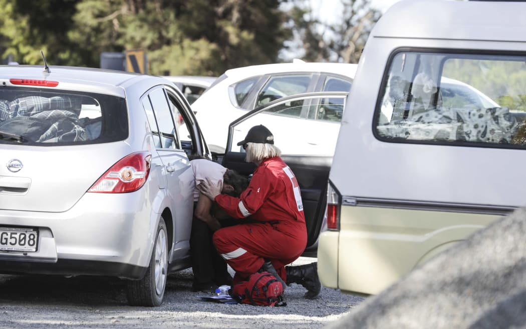 Red Cross worker supports fire evacuee at a road block
