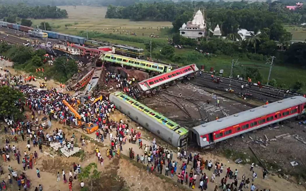 Ten zrzut ekranu z wideo AFP zarejestrowanego 3 czerwca 2023 r. Pokazuje ludzi gromadzących się w miejscu zderzenia trzech pociągów w pobliżu Balasore, około 200 kilometrów (125 mil) od stolicy stanu Bhubaneswar we wschodnim stanie Odisha.  Co najmniej 288 osób zginęło, a ponad 850 zostało rannych w straszliwym zderzeniu pociągu w Indiach, poinformowali urzędnicy 3 czerwca, najbardziej śmiertelny wypadek kolejowy w kraju od ponad 20 lat.  (Zdjęcie: Jayanta SHAW/AFPTV/AFP)