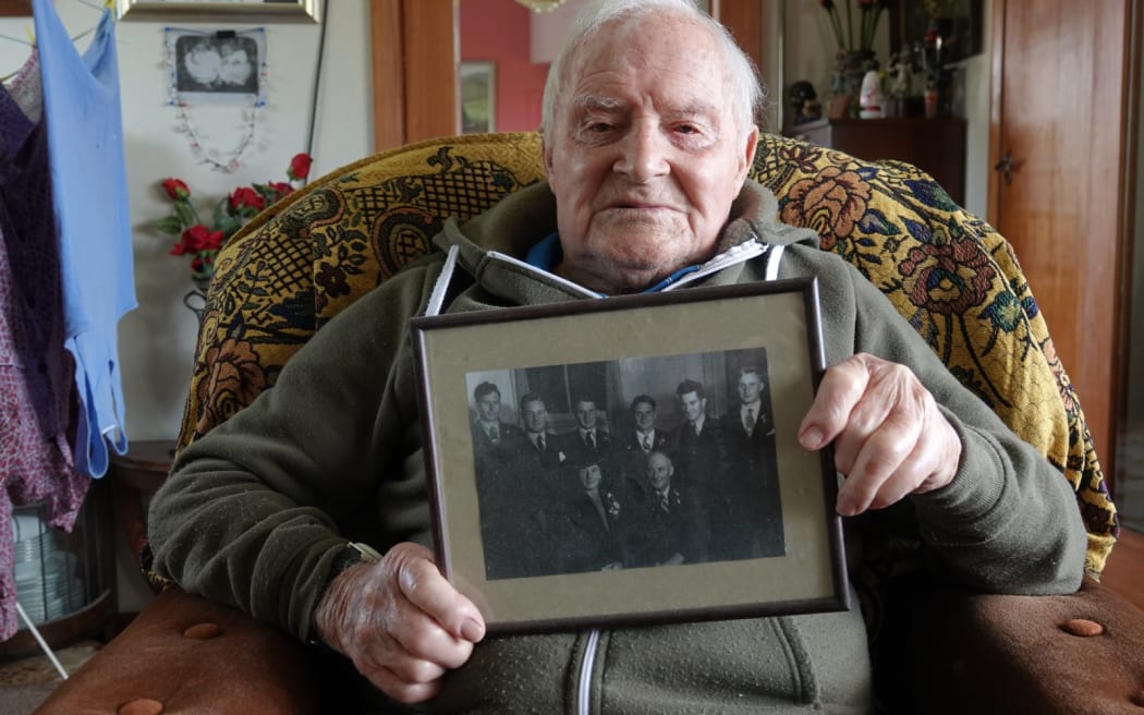 Oliver Candy holds a photo of himself with his five brothers and their parents.