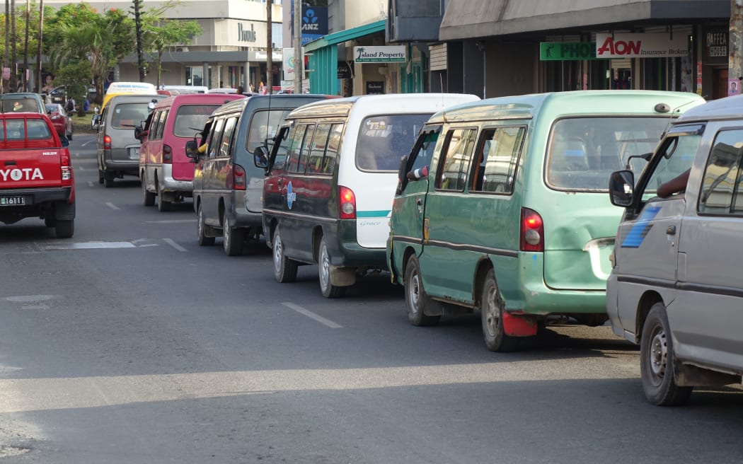 The vans that make up Port Vila's bus service line up along the main street.