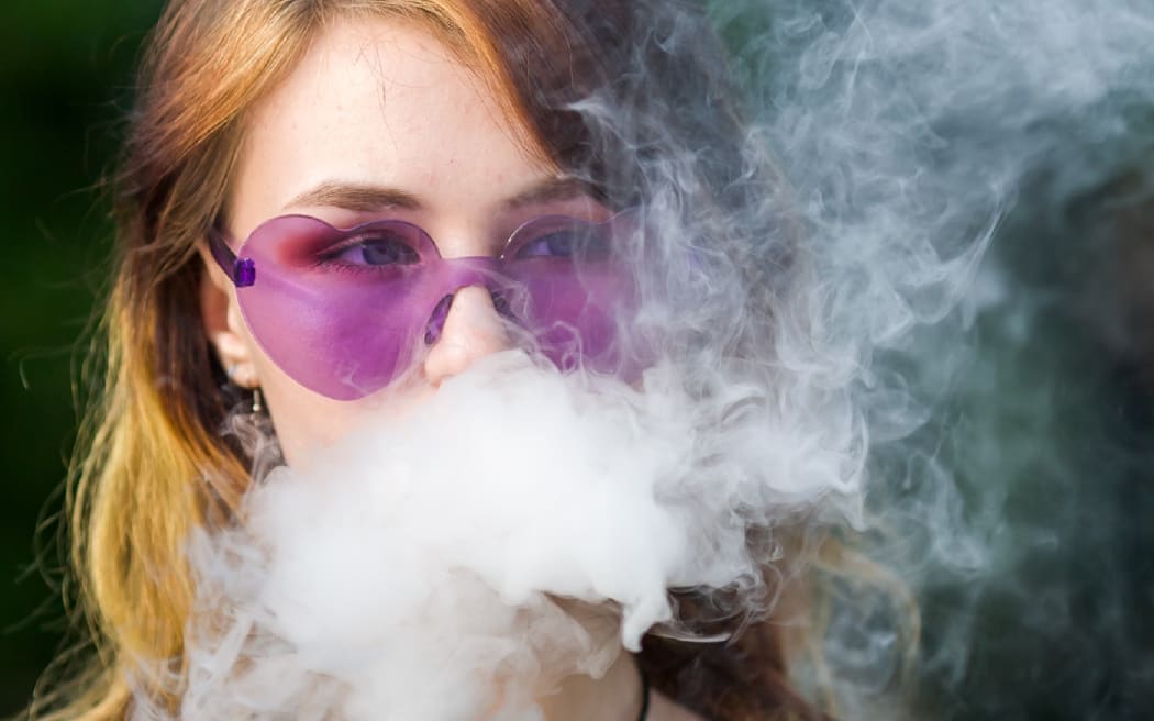 A teenager vaping an e-cigarette.