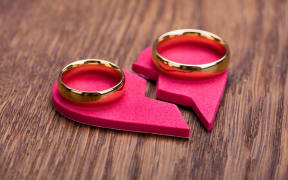69590501 - high angle view of golden ring on red broken heart at wooden desk