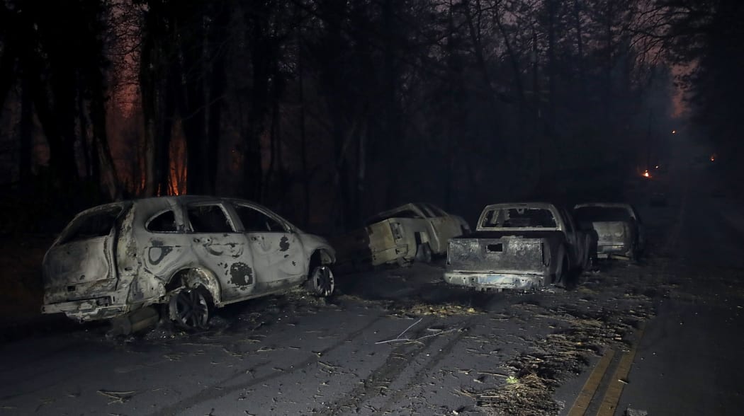 Abandoned burned out cars sit in the middle of the road after the Camp Fire moved through the area