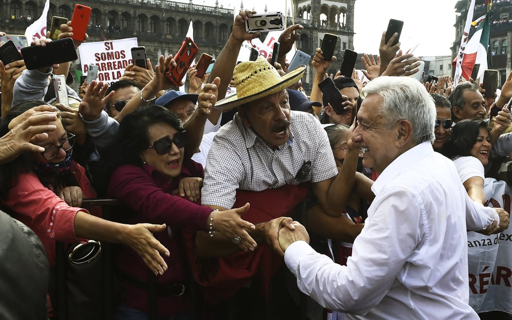 El presidente de México, Andrés Manuel López Obrador (der.), saluda a sus seguidores cuando llega a la plaza del Zócalo para celebrar su cuarto año en el cargo, en la Ciudad de México, el 27 de noviembre de 2022. (Foto: CLAUDIO CRUZ / AFP)