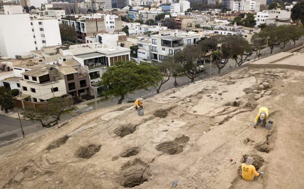 Aerial view showing workers excavating in the Huaca (Sanctuary) Pucllana, in the heart of a residential area in the district of Miraflores in Lima, where they uncovered a mummy belonging to the pre-Inca Ychsma culture buried in a shallow funeral chamber on an ancient sanctuary originally built by the Lima etnia on September 5, 2023. The Ychsma formed around 1100 AD following the breakup of the War Empire, whose autonomy lasted until around 1450, when they were absorbed into the Incan Empire that lived in what is now considered the central Peru coastline. (Photo by Cris BOURONCLE / AFP)