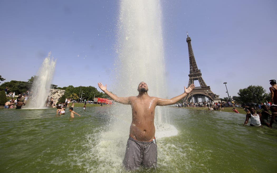 رجل يستريح عند نوافير تروكاديرو مقابل برج إيفل في باريس في 18 يونيو 2022 ، وسط درجات حرارة عالية قياسية في جميع أنحاء فرنسا وأوروبا الغربية.