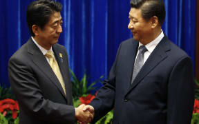 China's President, Xi Jinping, right, shakes hands with Japan's Prime Minister, Shinzo Abe.