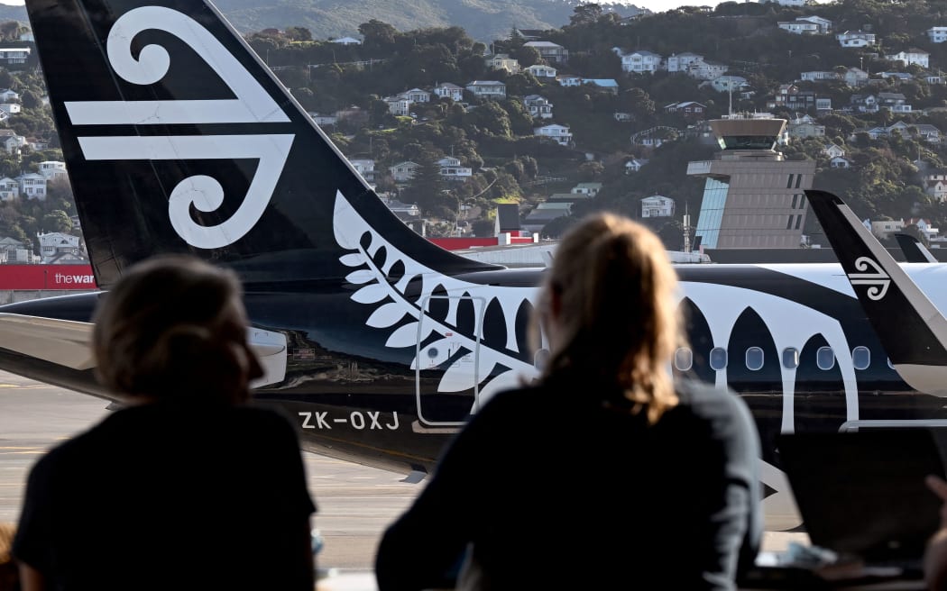 A photo taken on June 27, 2022 shows passengers looking at an Air New Zealand planes as they wait for their flight at Wellington Airport. (Photo by William WEST / AFP)