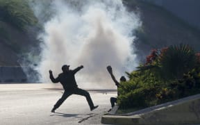 Opponents of Venezuela's President Nicolas Maduro throw stones at soldiers loyal to the president inside La Carlota airbase in Caracas, Venezuela, Tuesday, April 30, 2019.