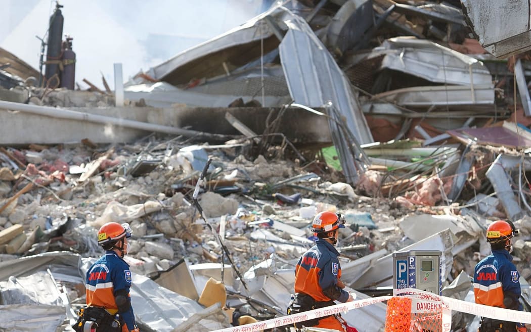 Japanese rescuers walk past the smoking ruins of the CTV building where 4in Christchurch on February 24, 2011, two days after a deadly earthquake rocked New Zealand's second city