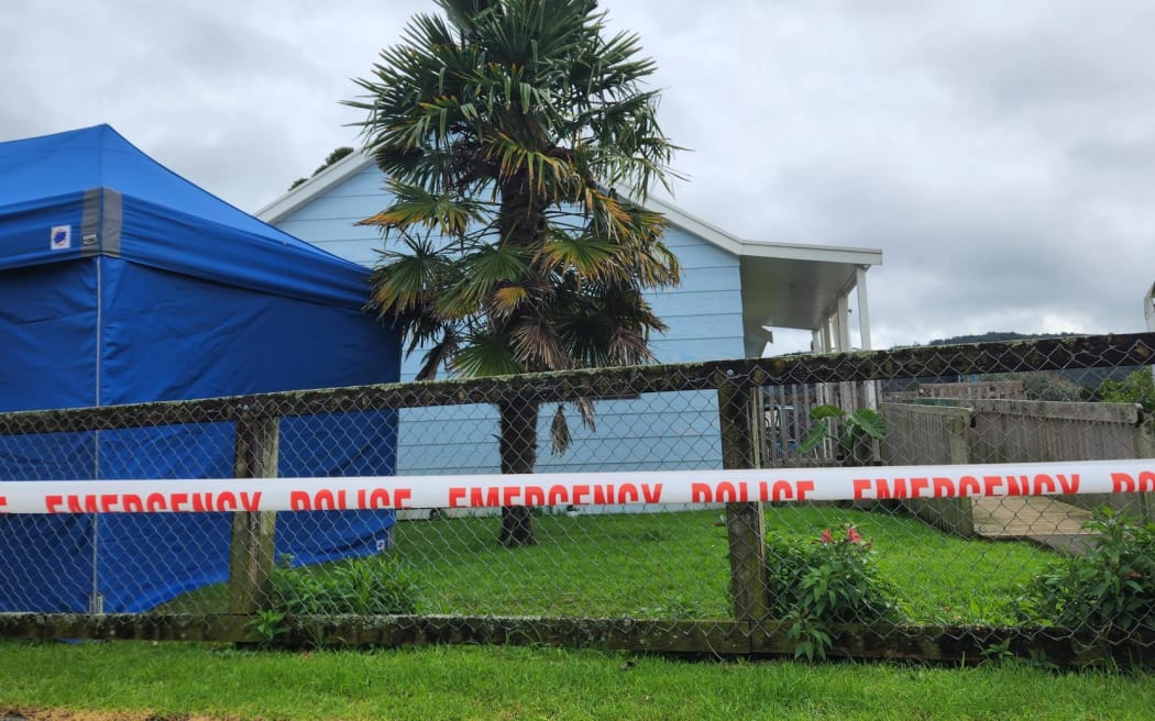 Police are executing a search warrant at a house on Taraire Street in relation to the investigation into the homicide of Linda Woods. At least four officers are guarding the cordoned house and other officers can be seen rummaging through rubbish bins on the property.