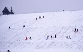 People sledge down a hillside at  Butterley Reservoir in Marsden, northern England on January 14, 2021 as heavy snow fell on parts of the UK