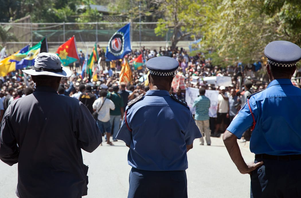 Papua New Guinea police officers watch on during a protest rally in 2013.