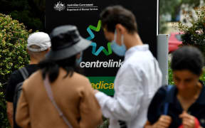 People wait in a queue to receive benefit payouts, including unemployment and small business support as the novel coronavirus inflicts a toll on the economy, at a Centerlink payment centre in downtown Sydney on 27  March 2020.