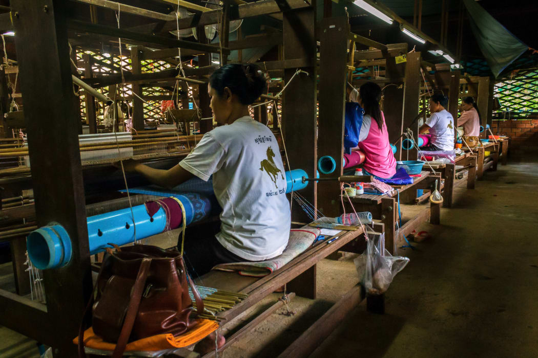 Women weave patterns with silk in Siem Reap Cambodia.