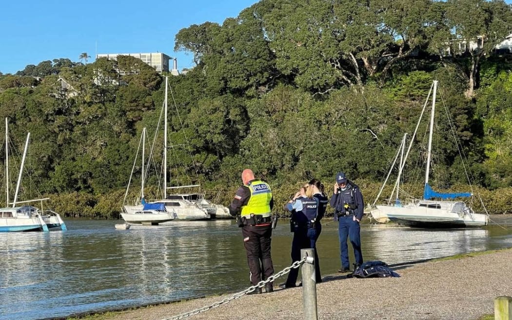Police officers watch on as a man, believed to be a police officer, ditches his uniform and heads out into the water.