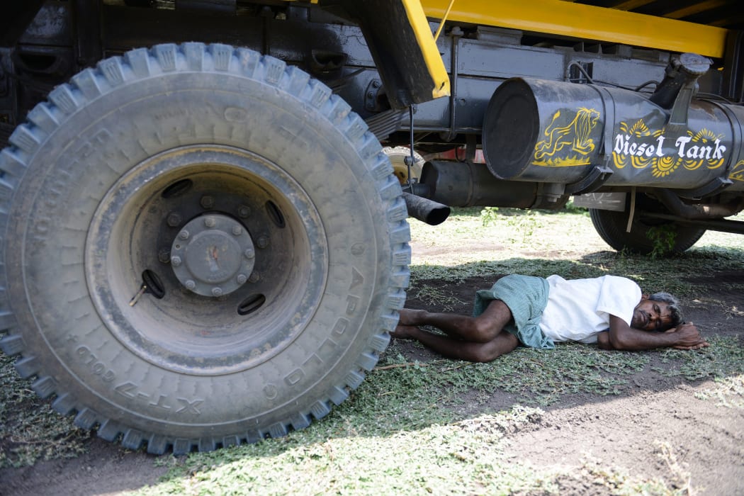 An Indian man rests under a transport vehicle on the outskirts of Hyderabad.