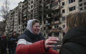 A woman reacts as she stands outside destroyed apartment blocks following shelling in the northwestern Obolon district of Kyiv on March 14, 2022.