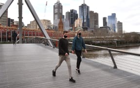 A couple walks on a footbridge over the Yarra River in the Southbank district of Melbourne on 12 August 2020 during the city's Covid-19 lockdown.