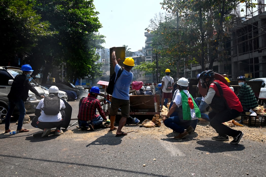 Protesters take cover behind makeshift barricades, made to obstruct security forces, during a demonstration against the military coup in Yangon on 28 February