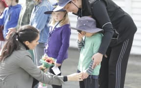 Meghan comforts a young boy who was waiting to catch a glimpse of the royal pair outside Maranui Cafe.
