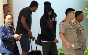 A refugee (3rd R) held under Australian custody in the Central Pacific island of Nauru is escorted by Cambodian police following his arrival at the Phnom Penh International airport on June 4, 2015.