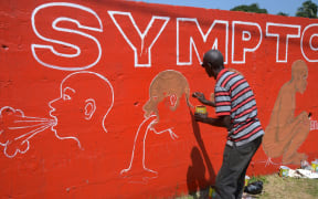 Liberian street artist Stephen Doe paints a mural in Monrovia to inform people about the symptoms of Ebola.