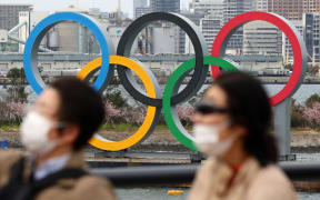 People wearing a mask walk near the Olympics' mark in Odaiba, Tokyo, amid the outbreak of a new coronavirus in Japan.