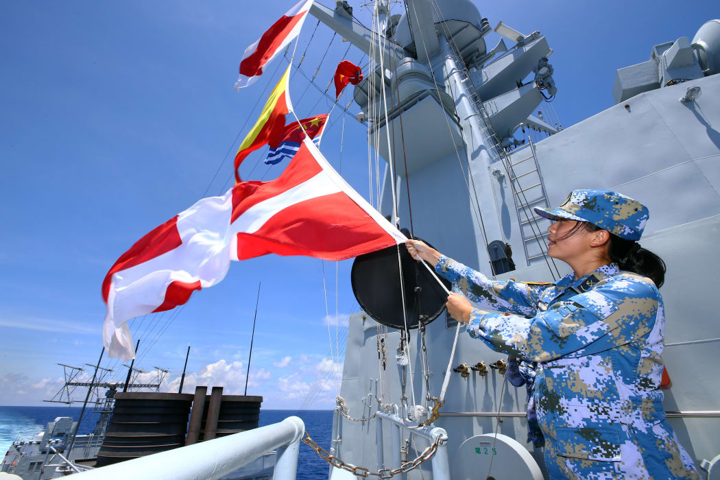 A Chinese navy soldier hangs signal flags on missile destroyer Hefei during a military exercise in the South China Sea.