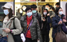 Mask-clad commuters get off a train at a Mass Rapid Transit (MRT) stop in Taipei following the Lunar New Year holidays on January 30, 2020.
