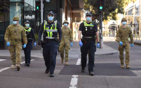 A group of police and soldiers patrol the Docklands area of Melbourne on August 2, 2020, after the announcement of new restrictions to curb the spread of the COVID-19 coronavirus.