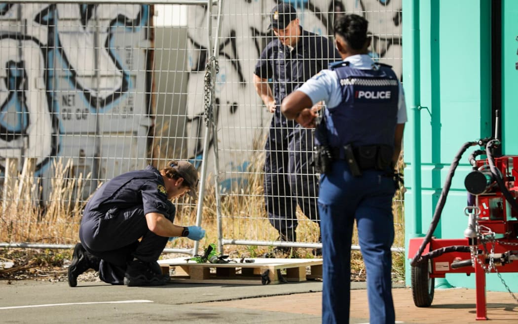 Police officers investigate an object inside a cordon where a suspicious package was reported.