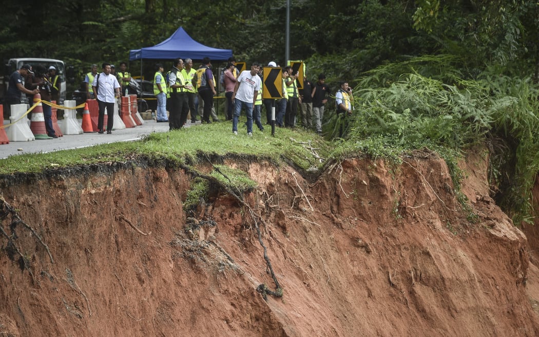 People inspect the damage after a landslide in Batang Kali, Selangor on December 16, 2022. - Nearly 20 people, including four children, were killed when a landslide struck a campsite at a Malaysian farm on Friday, officials said, with rescuers scouring the muddy terrain for those still missing. (Photo by Arif Kartono / AFP)