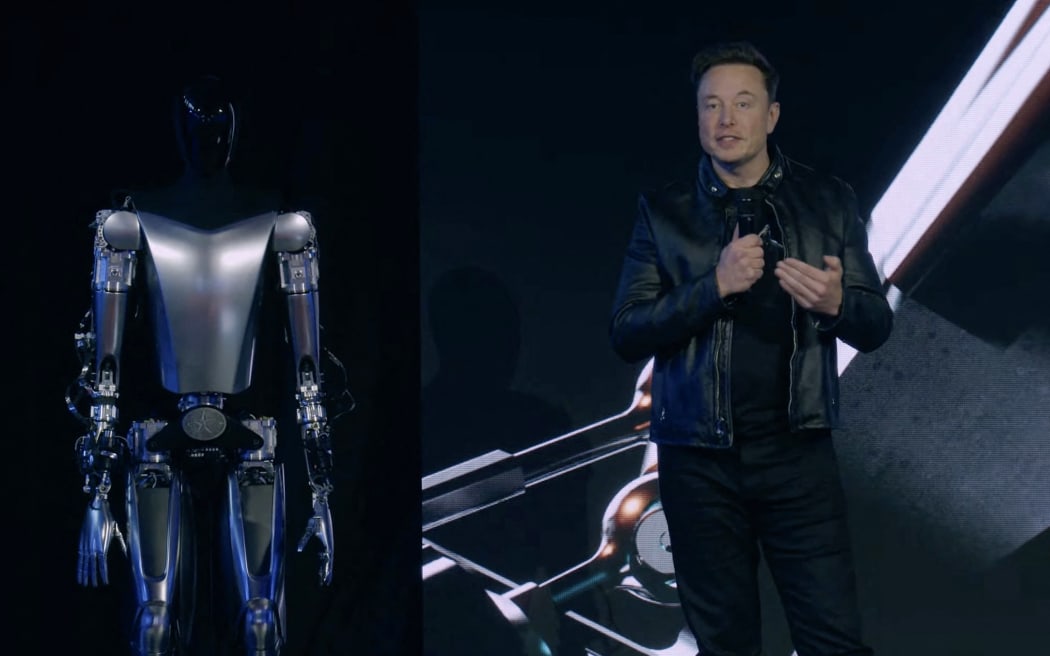 This video screen grab made from Tesla AI Day 2022 livestream shows Elon Musk standing on stage next to Optimus the humanoid robot in Palo Alto, California on September 30, 2022. (Photo by Tesla / AFP) / RESTRICTED TO EDITORIAL USE - MANDATORY CREDIT 