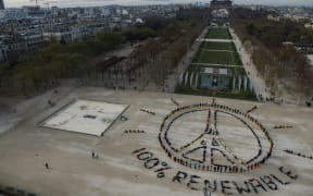 People make the "Pray for Paris" sign along with the slogan "100 percent renewable" in Paris on the sidelines of the COP21 climate change conference.