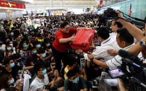 A woman gives her luggage to security guards as she tries to enter the departures gate during another demonstration by pro-democracy protesters at Hong Kong's international airport on August 13, 2019.