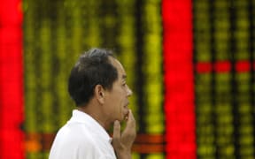 An investor looks at prices of shares (red for price rising and green for price falling) at a stock brokerage house in Huaibei city, Anhui province, China, 27 July 2015.