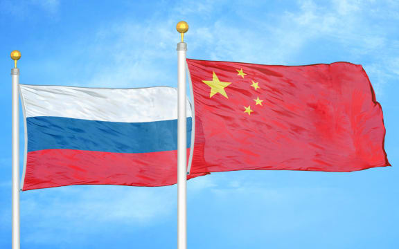 Russia and China two flags on flagpoles and blue cloudy sky background