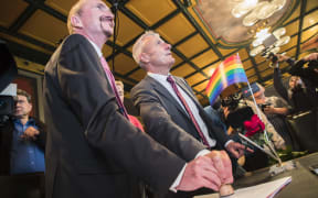 Bodo Mende (C) and Karl Kreile (L) stamp their wedding certificate during their wedding ceremony in Schoeneberg town hall in Berlin, Germany on October 1, 2017.