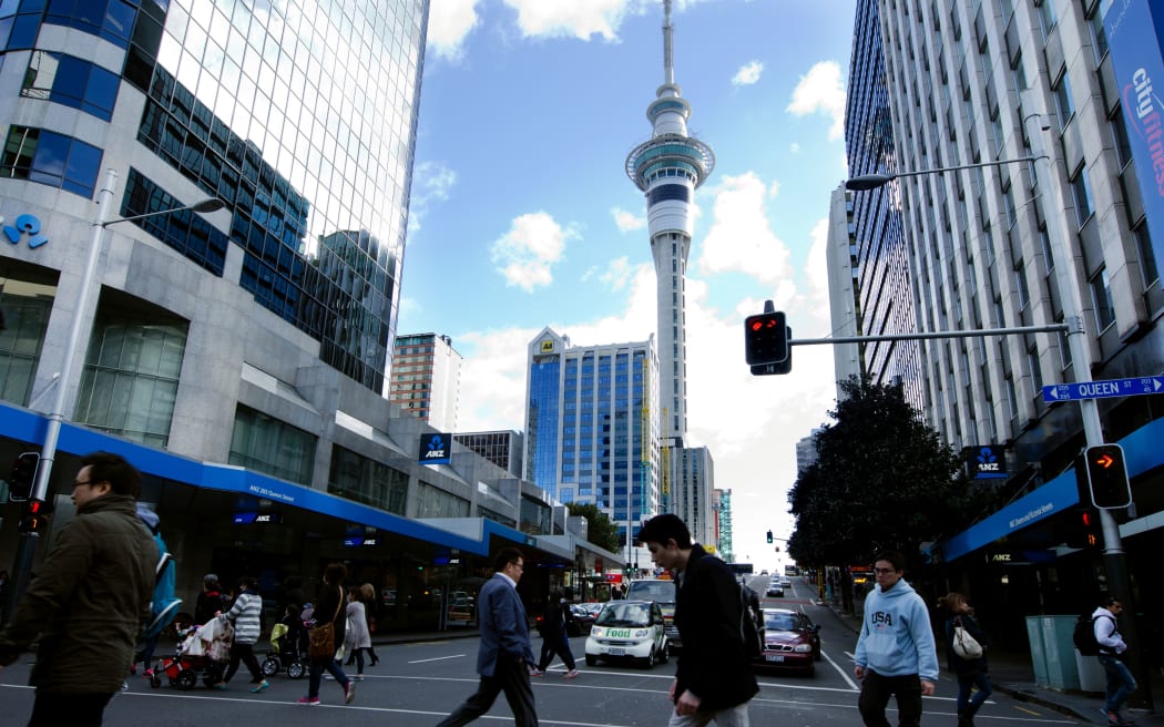奥克兰，新西兰- 5月29日：在皇后街道上的交通有Skytower的在2013年5月29日的背景中。它是一条主要商业大道在奥克兰中央商务区，新西兰的主要人口中心。