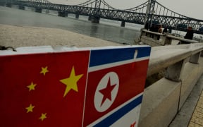 The Chinese and North Korean flags attached to a railing as trucks carrying Chinese-made goods cross into North Korea on the Sino-Korean Friendship Bridge at the Chinese border town of Dandong on December 18, 2013.
