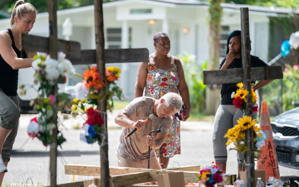 JACKSONVILLE, FLORIDA - AUGUST 28: Floridian Will Walsh builds a cross at a memorial for Jerrald Gallion, Angela Carr and Anolt Joseph Laguerre Jr., as a person grieves, near a Dollar General store where the were shot and killed two days earlier on August 28, 2023 in Jacksonville, Florida. According to law enforcement, the shooter specifically targeted the Black victims because of their race.   Sean Rayford/Getty Images/AFP (Photo by Sean Rayford / GETTY IMAGES NORTH AMERICA / Getty Images via AFP)