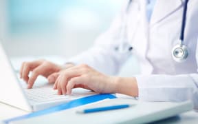 An image of a doctor typing on a laptop