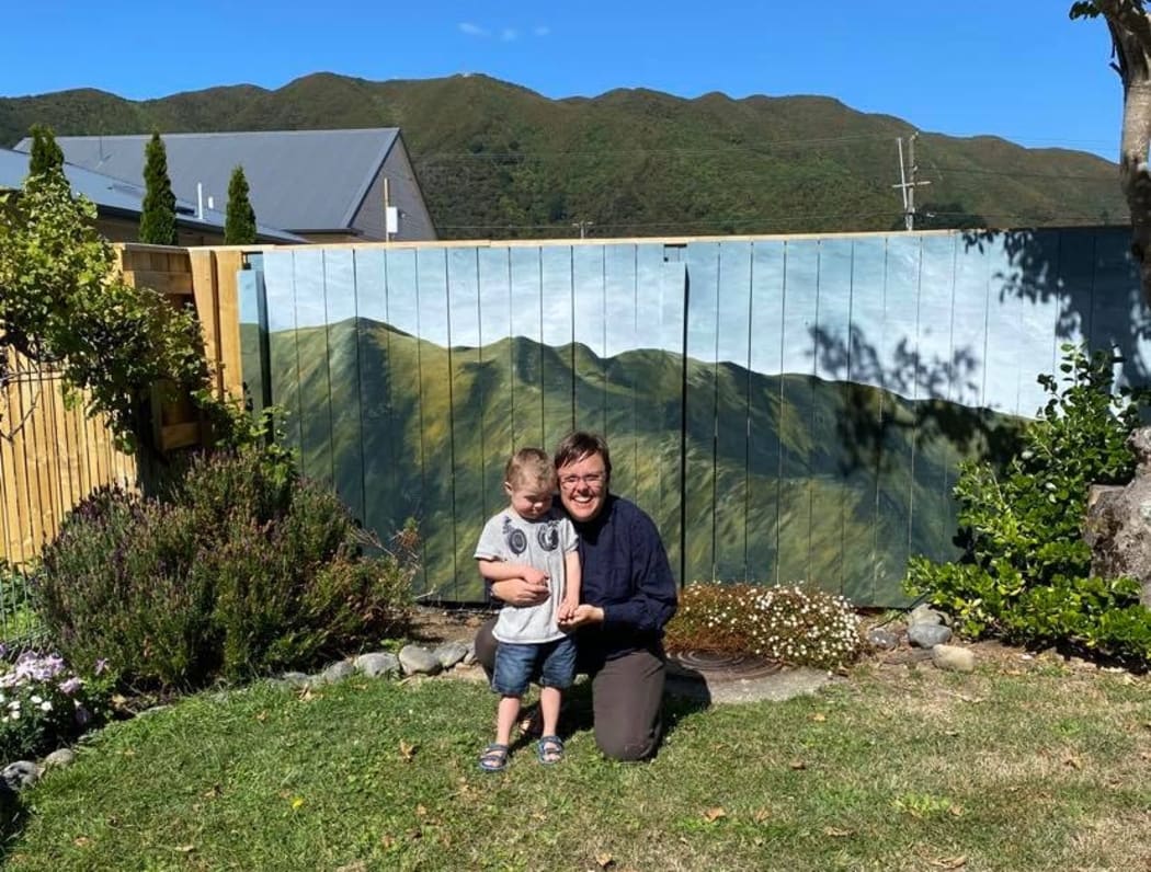 Artist Hana Carpenter and her son in front of the mural of the hills.