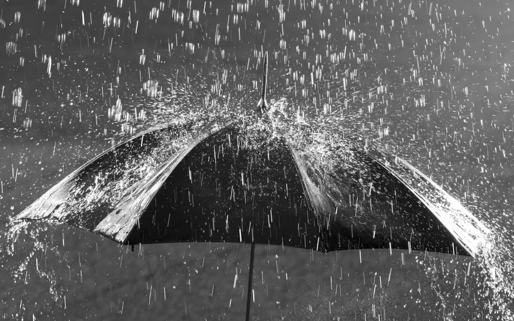 black and white photo of umbrella in heavy rain
